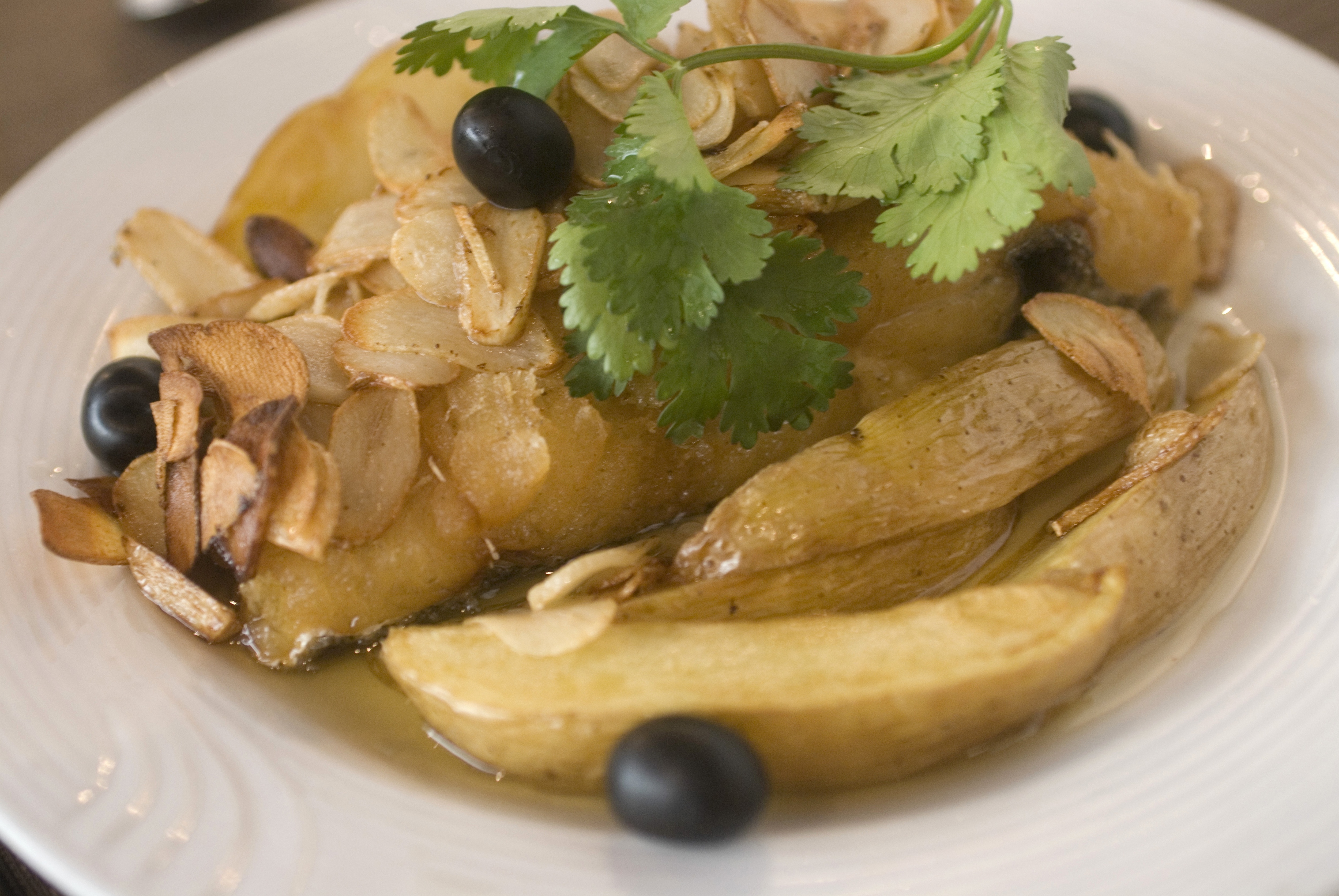 MACAU, MACAU S A R , CHINA - 2009/09/07: A dish of bacalhau, or salt cod fish, at the A Lorcha restaurant. This is a typical Portuguese meal and is served with potatoes, garlic slices, black olives and copious olive oil. (Photo by Stefan Irvine/LightRocket via Getty Images)