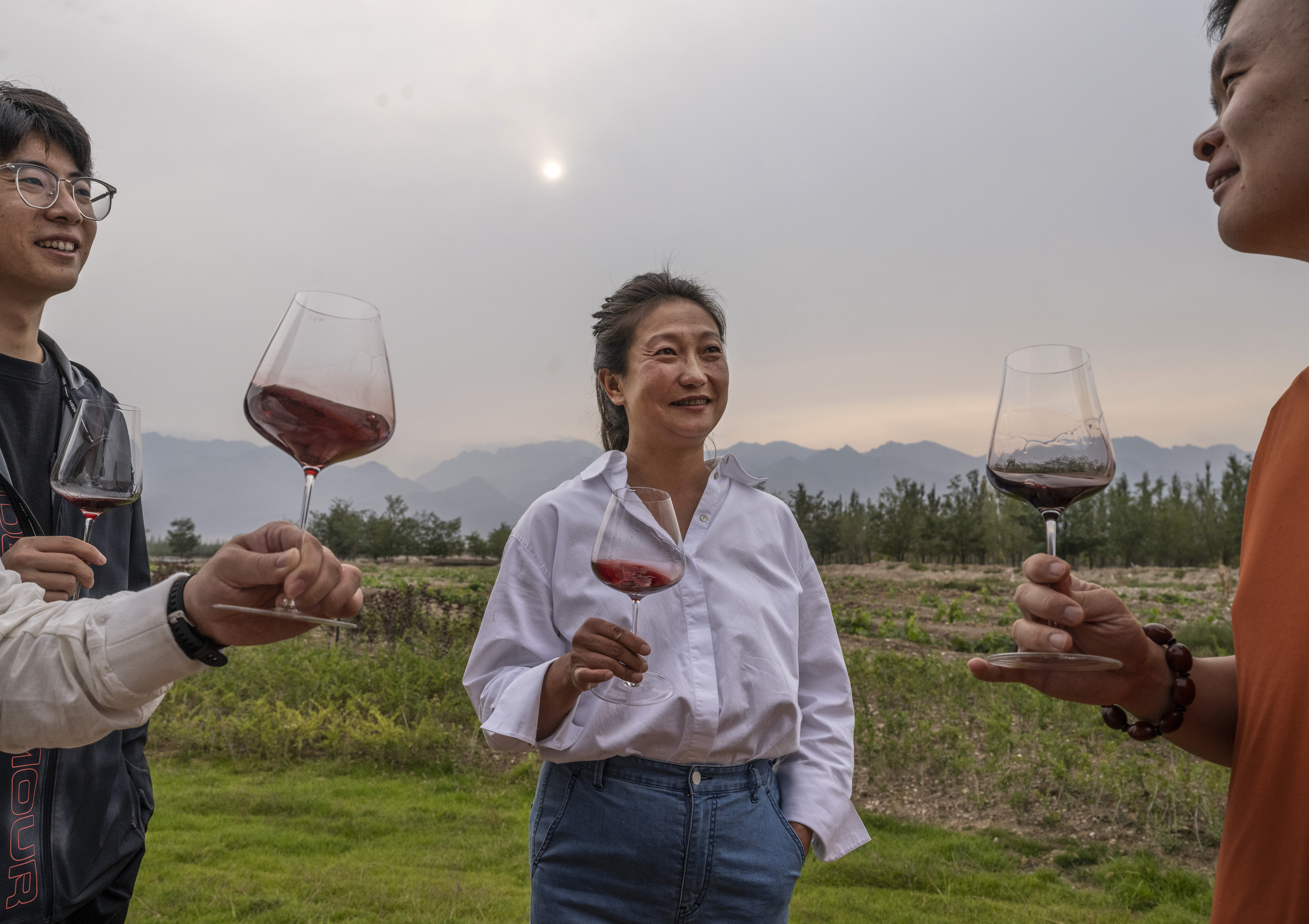 JIN SHAN, CHINA - SEPTEMBER 18: Vineyard owner and winemaker Emma Gao talk with colleagues as they taste Gao