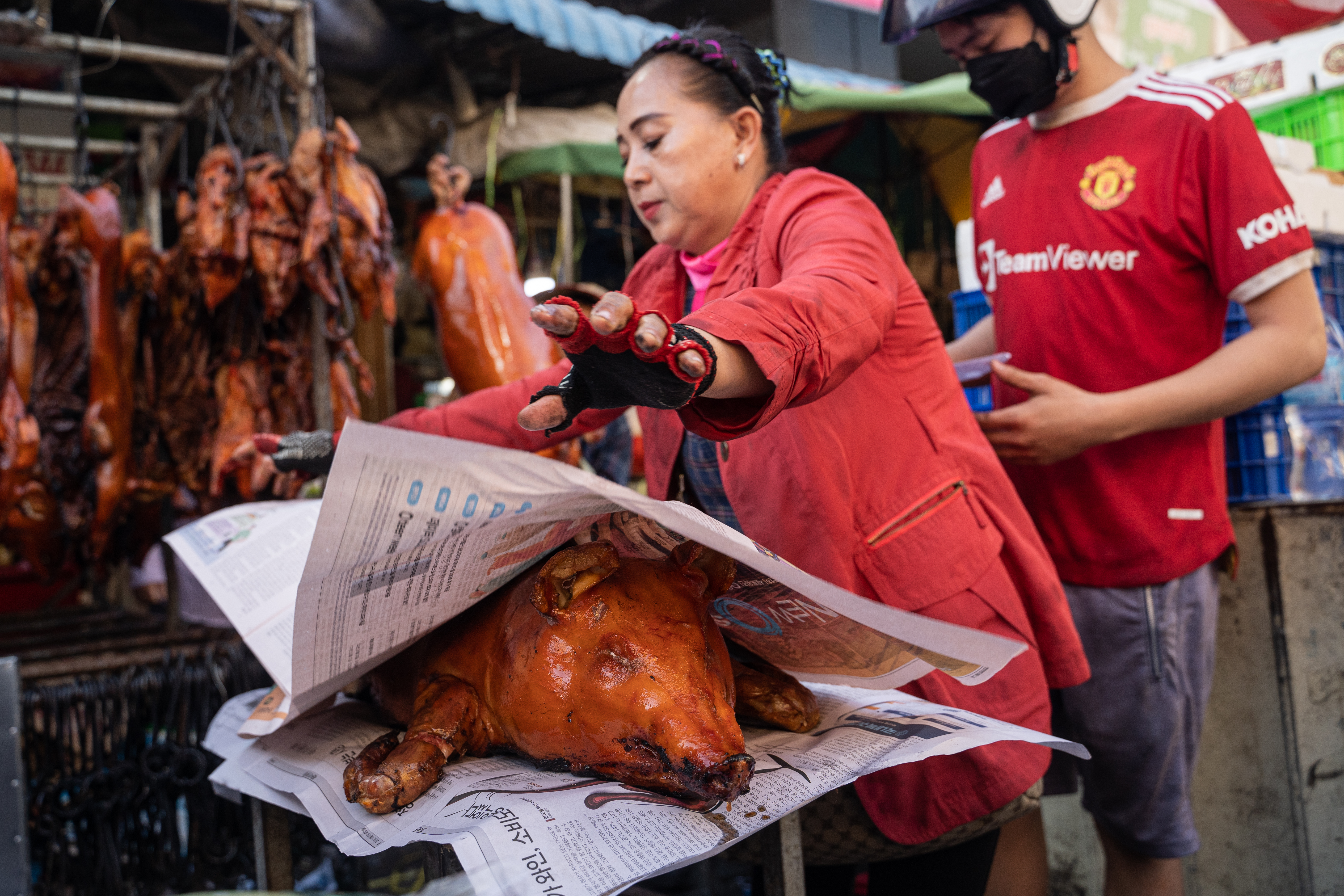 PHNOM PENH, CAMBODIA - JANUARY 21: A vendor wraps a roasted pig at a market ahead of Lunar New Year on January 21, 2023 in Phnom Penh, Cambodia. The Chinese diaspora of Southeast Asia is celebrating a lively Lunar New Year, as COVID-19 restrictions have been removed. It is traditionally a time for people to meet their relatives and take part in celebrations with families. In Cambodia, which has aligned it self closely with China and where China is investing heavily, celebration feasts feature suckling pigs, among other highlights. (Photo by Cindy Liu/Getty Images)