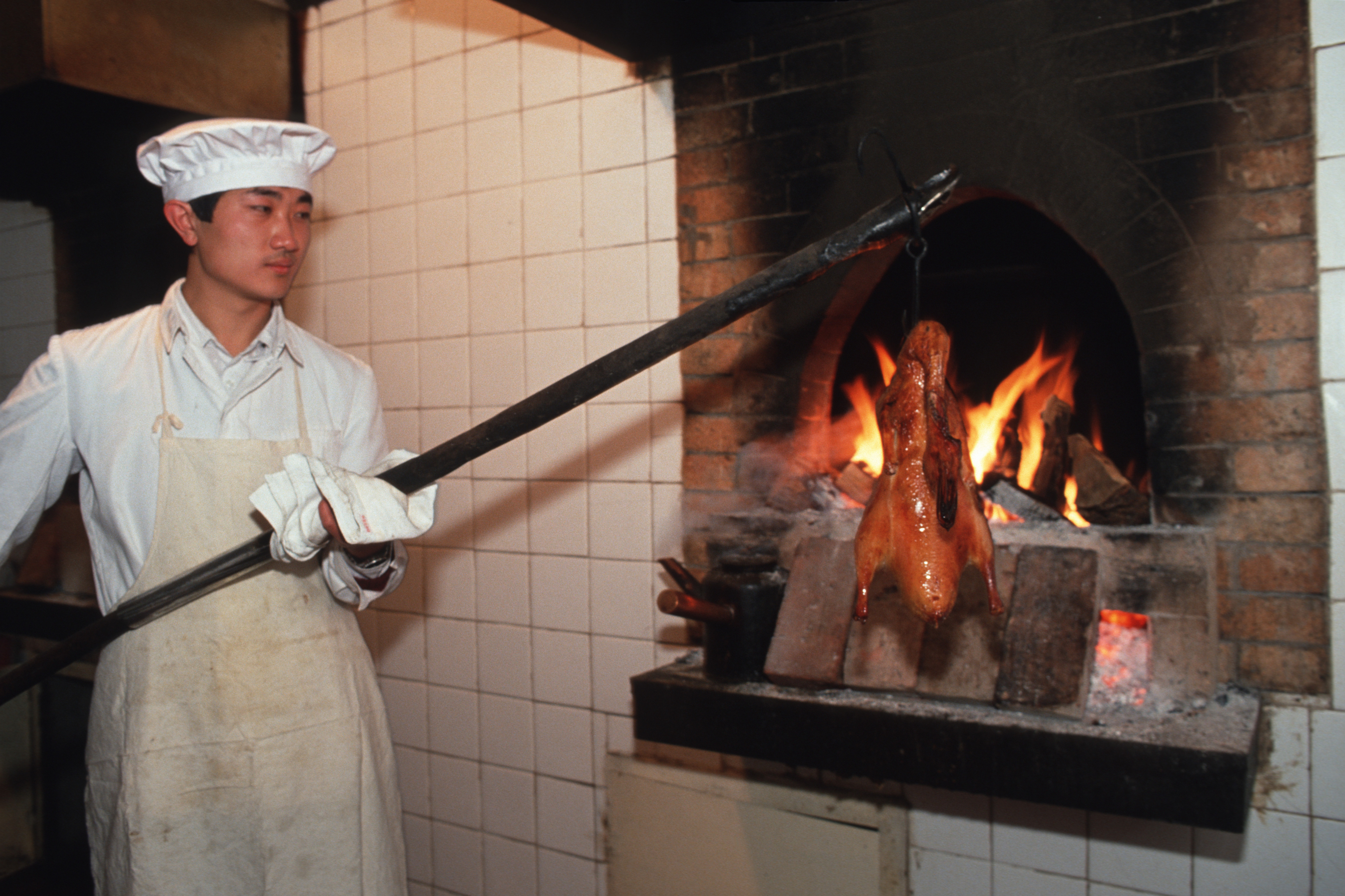 BEJING, CHINA - 1992/01/01: After being forced fed for 59 days, to make them fat, the ducks are slaughtered and then roasted in the kitchen at Jin Song Quan Ju De Roast Duck Restaurant in Beijing.

The origin of the Peking Duck dates back to the Ming Dynasty, about 600 years ago. Cooks from all over China travelled to the capital Beijing to cook for the Emperor. With the eventual fall of the Ching dynasty in 1911, court chefs who left the Forbidden City set up restaurants around Beijing and brought the Peking Duck and other delicious dishes to the masses. (Photo by Gerhard Joren/LightRocket via Getty Images)