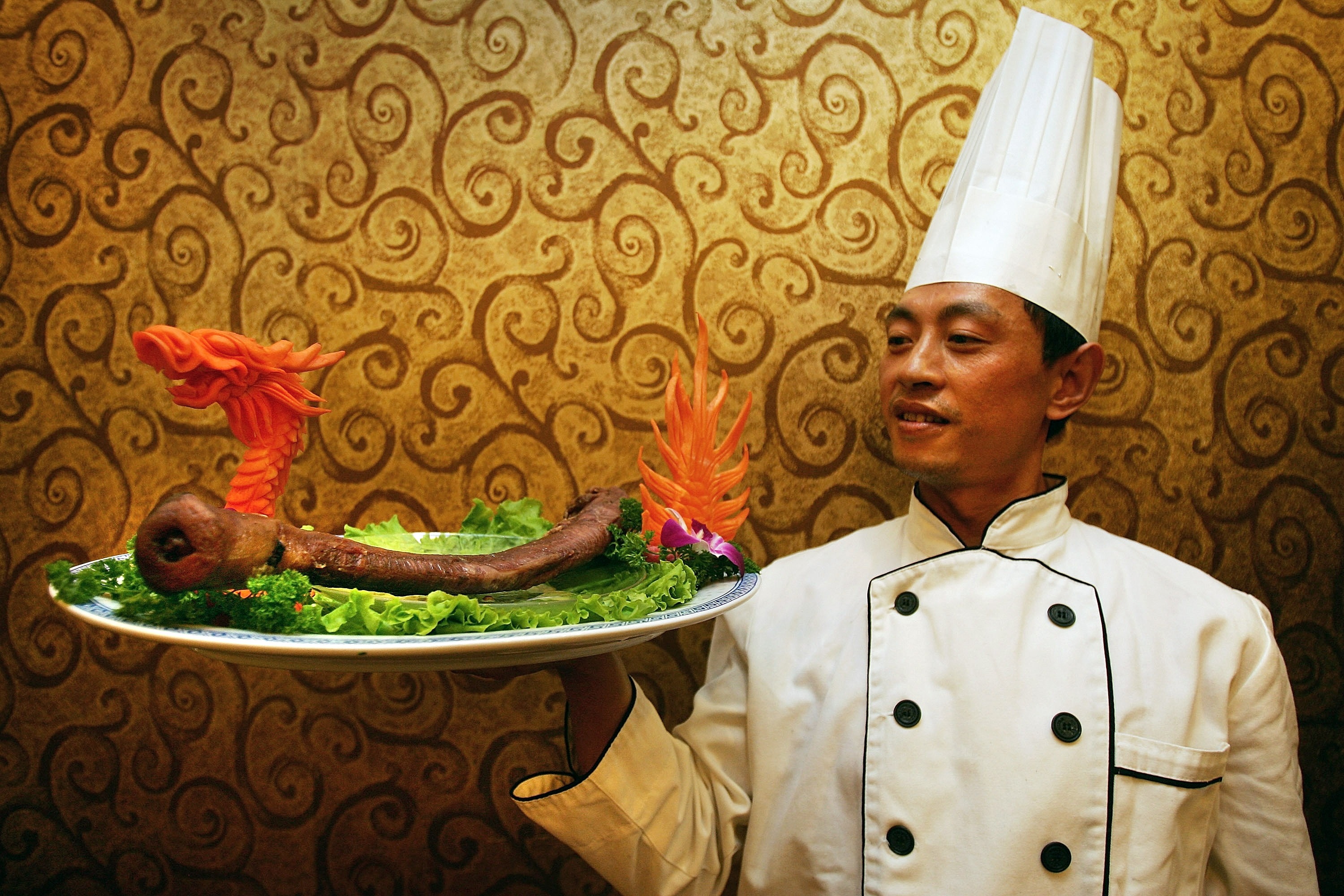BEIJING - SEPTEMBER 07:  A cook poses with a plate of yak penis at the Guolizhuang Penis Restaurant on September 7, 2007 in Beijing, China. The restaurant offers more than 30 types of animal-penis dishes which can cost from 500 yuan up to 90,000 yuan. It is believed that eating an animal
