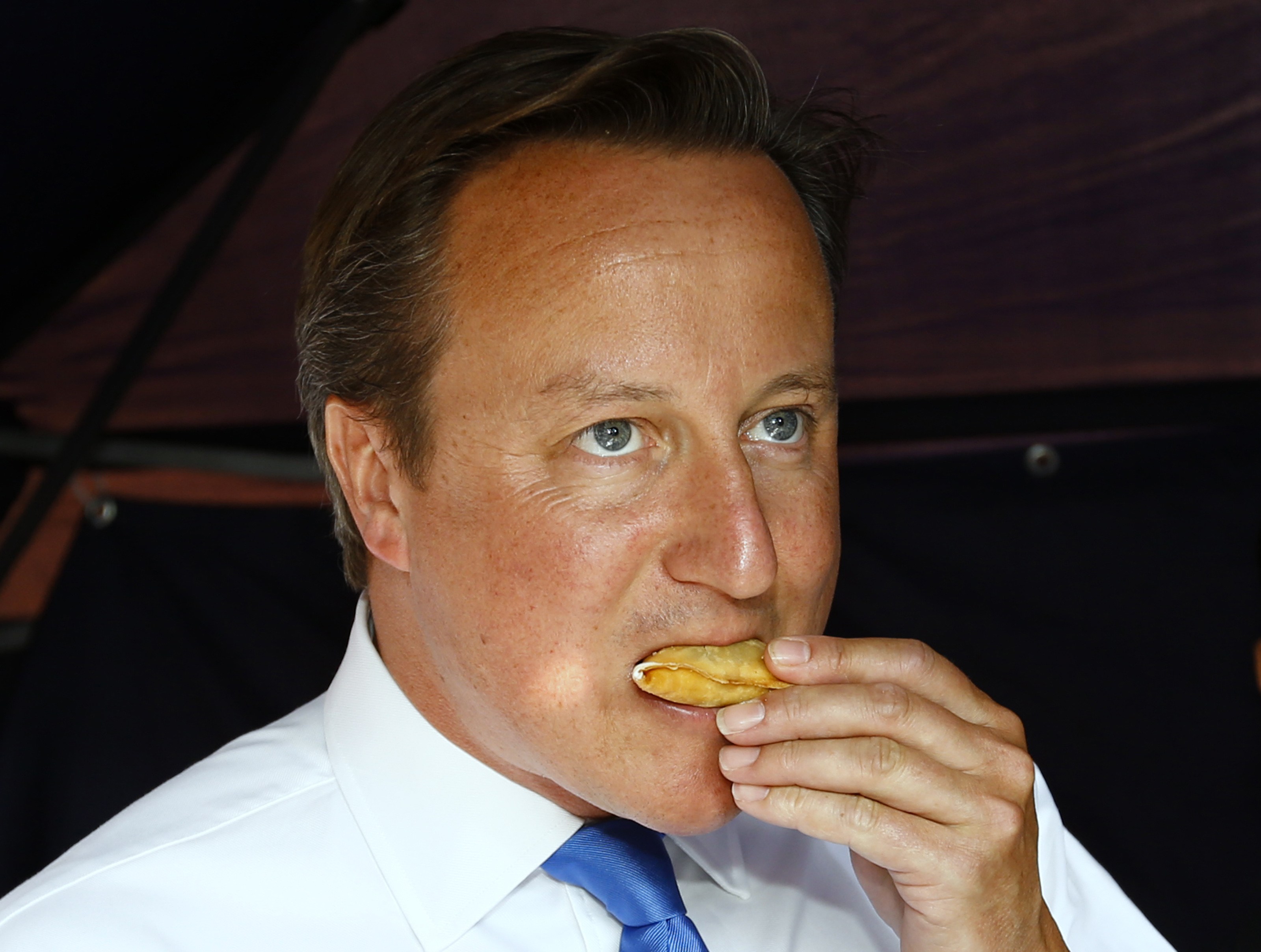 MANCHESTER, ENGLAND - AUGUST 7:  Prime Minister David Cameron eats a samosa during a visit to the Jamia Mosque on August 7, 2013 in Manchester, England. Cameron reportedly also called the Spanish Prime Minister today over a potential euro levy on vehicles entering Gibraltar.  (Photo by Darren Staples - WPA Pool/Getty Images)
