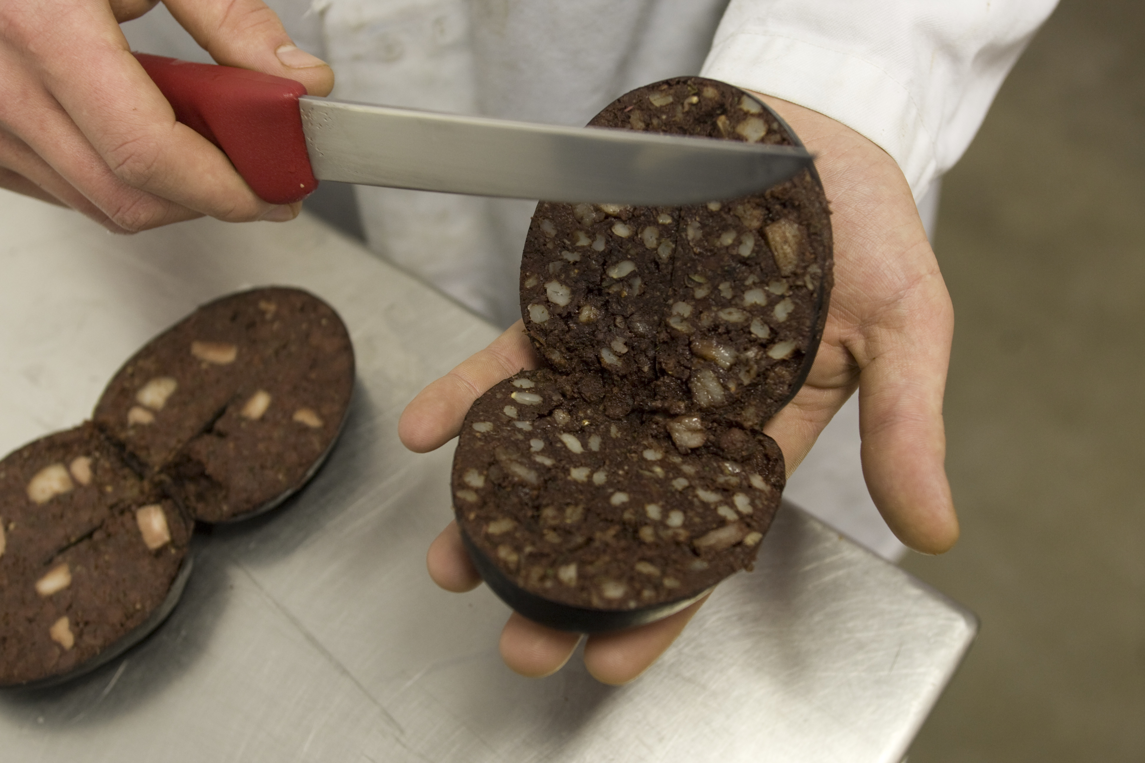Freshly-made traditional Bury black pudding being exaqmined at R. S. Ireland