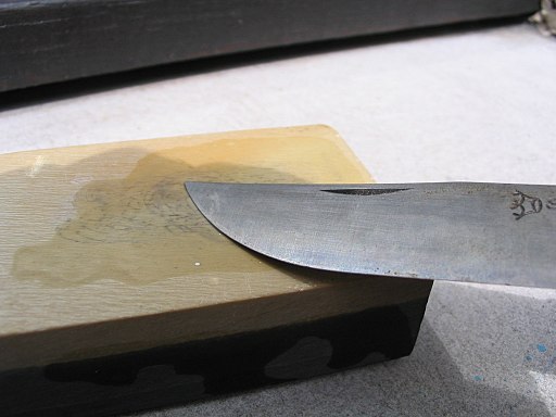 Opinel + Coticule : sharpening the knife on a coticule from Vielsalm in Belgium – Author: user:xofc – CC BY-SA 4.0