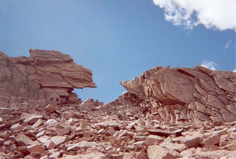 The Keyhole as seen from the Boulder Field. A small stone shelter (Agnes Vaille Memorial) approximately 10 feet (3 m) high that sits on the left side of the Keyhole gives a sense of scale – Author: Benwildeboer – CC BY-SA 3.0