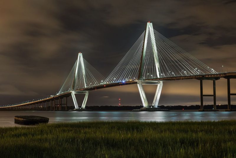 Arthur Ravenel Jr. Bridge (also known as the Cooper River Bridge) at night, looking northwest from Point Pleasant, South Carolina – Author: Juliancolton – CC BY-SA 4.0