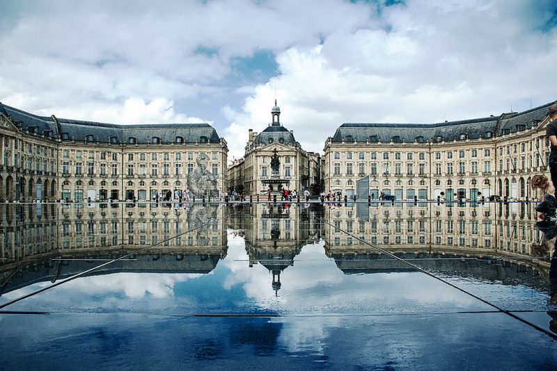 Place de la Bourse with the Hotel and Palais de la Bourse in Bordeaux. In front, the Miroir d’eau can be seen. – Author: Xellery – CC BY-SA 3.0