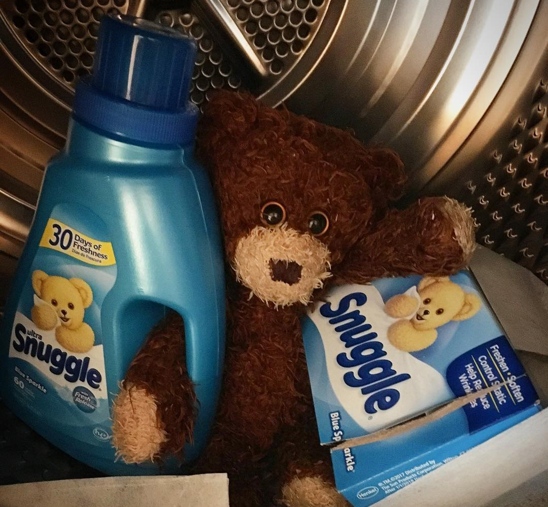 fabric softener getting held by a cute stuffed animal inside of a dryer 