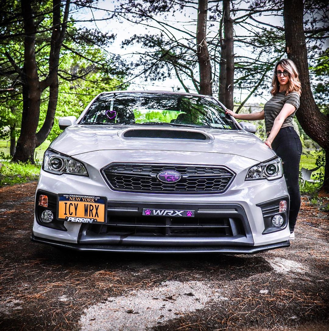 subaru and young lady standing there next to it