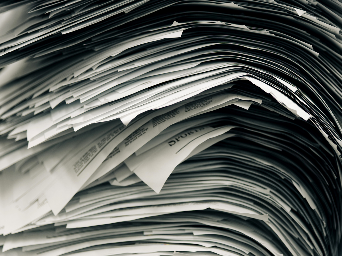 A stack of newspaper proofs piled on an empty desk
