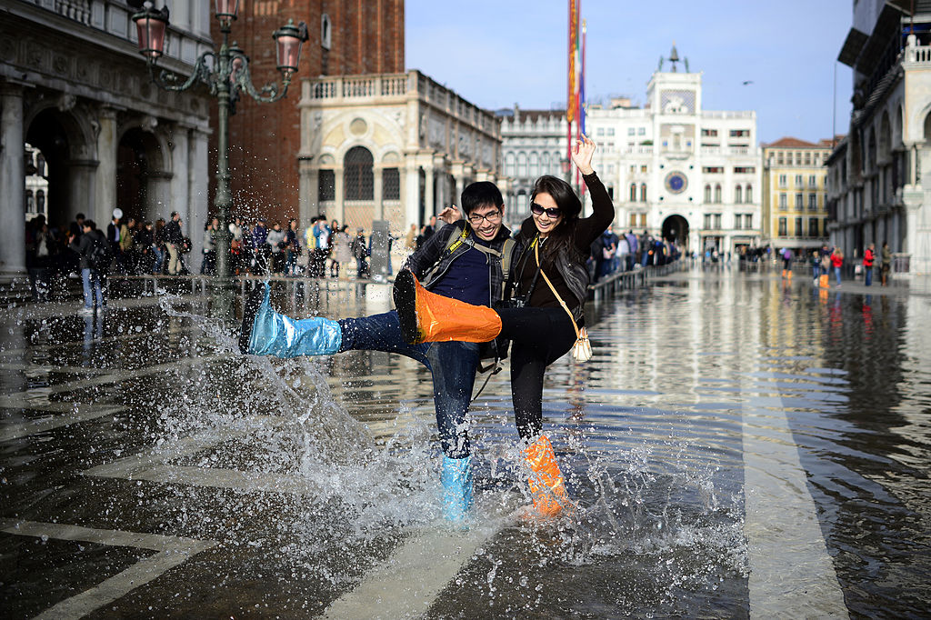 A just married Canadian couple on a honey moon trip in Venice plays with the water in front of the Doge's Palace-186794976