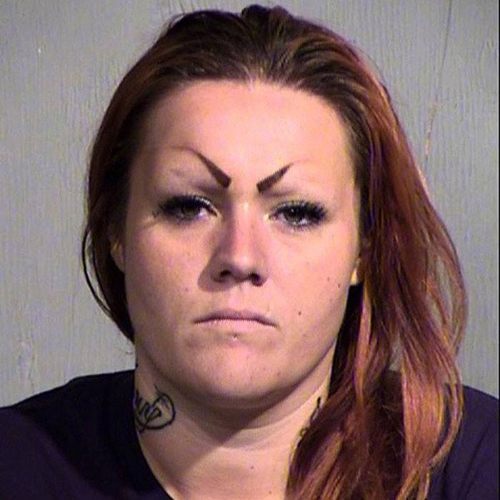 a mugshot of a woman with mean eyebrows