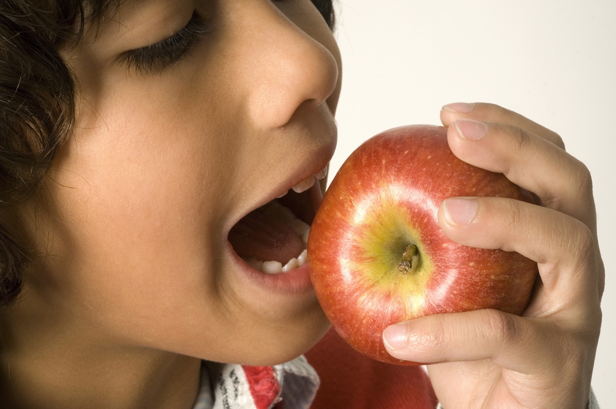 Close-up of boy eating apple.