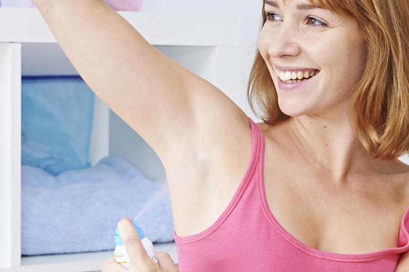 Woman applying spray deodorant.