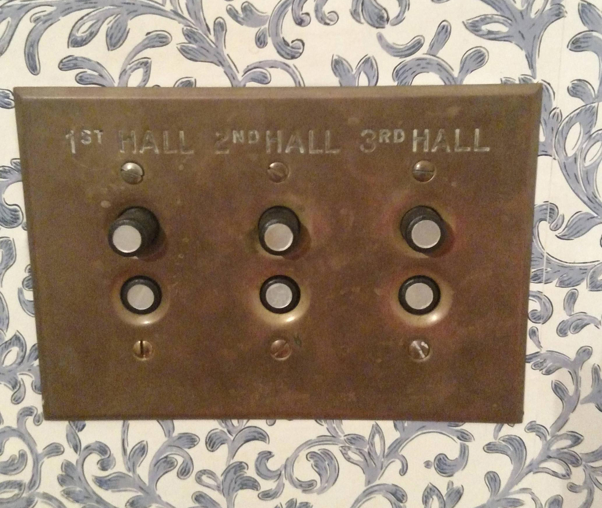 Old-fashioned button light switches hang on a wall.