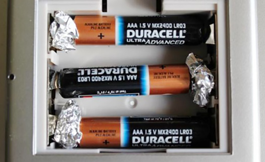 Aluminum foil pressed against battery 