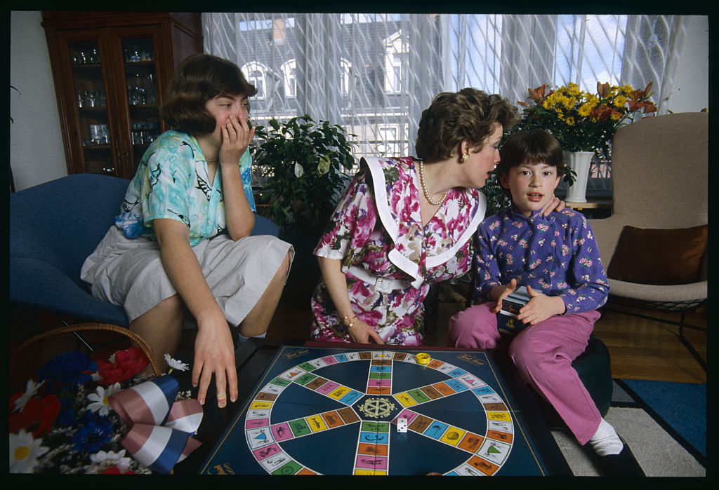Woman helps her younger daughter play a game