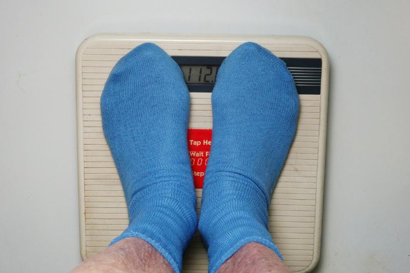 A person stands on a scale to weigh himself.