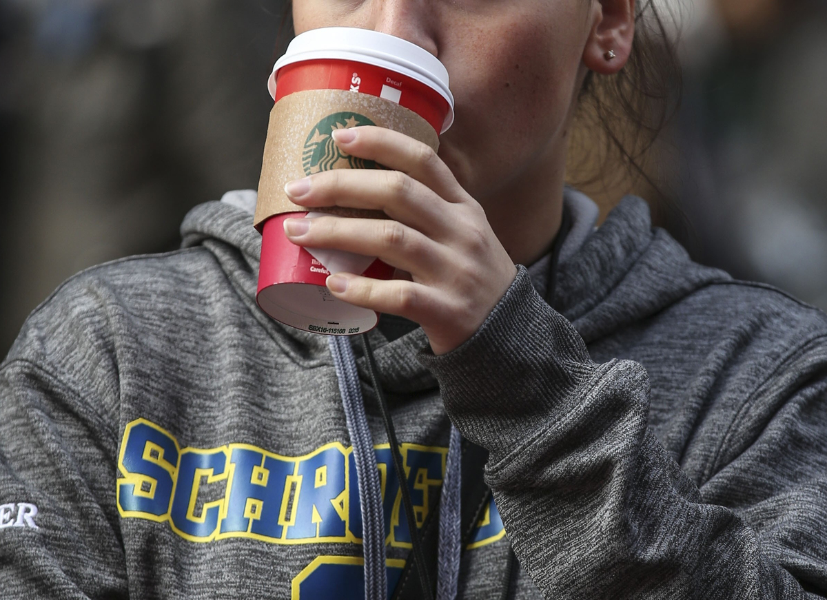 A woman drinks Starbucks coffee in a red cup.