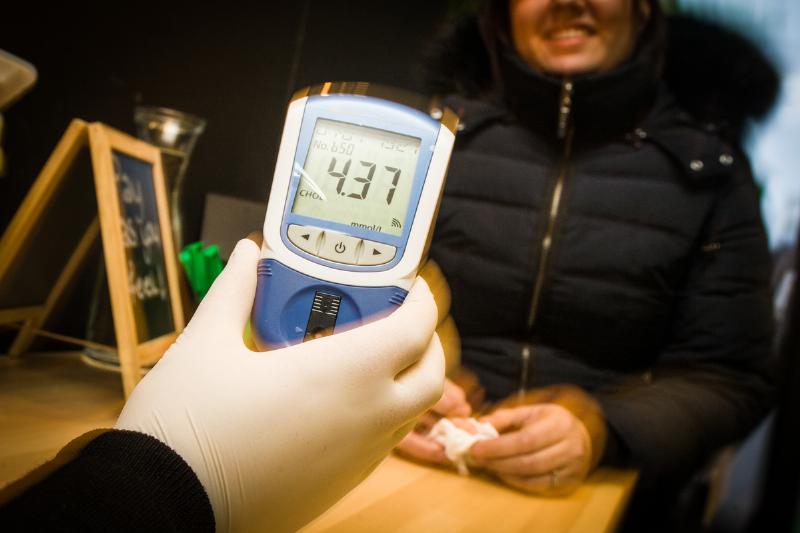 A man from the cholesterol foundation shows the result of a blood test for cholesterol screening.