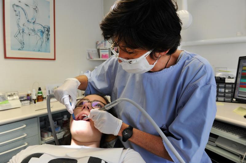 A dentist cleans a patient's teeth.