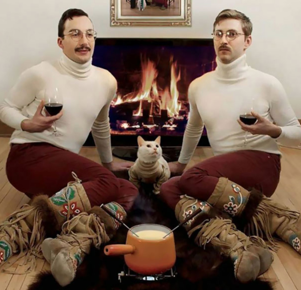 two guys in matching outfits (their cat has the same sweater too) with apot of fondue