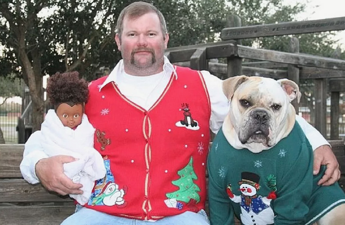 man in christmas vest with dog and baby doll