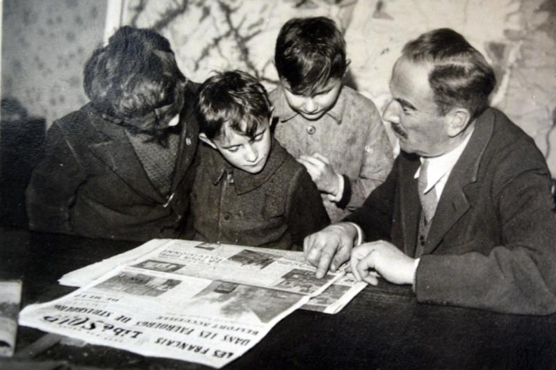French family reads newspaper outlining the liberation of towns in Alsace Lorraine 1944.