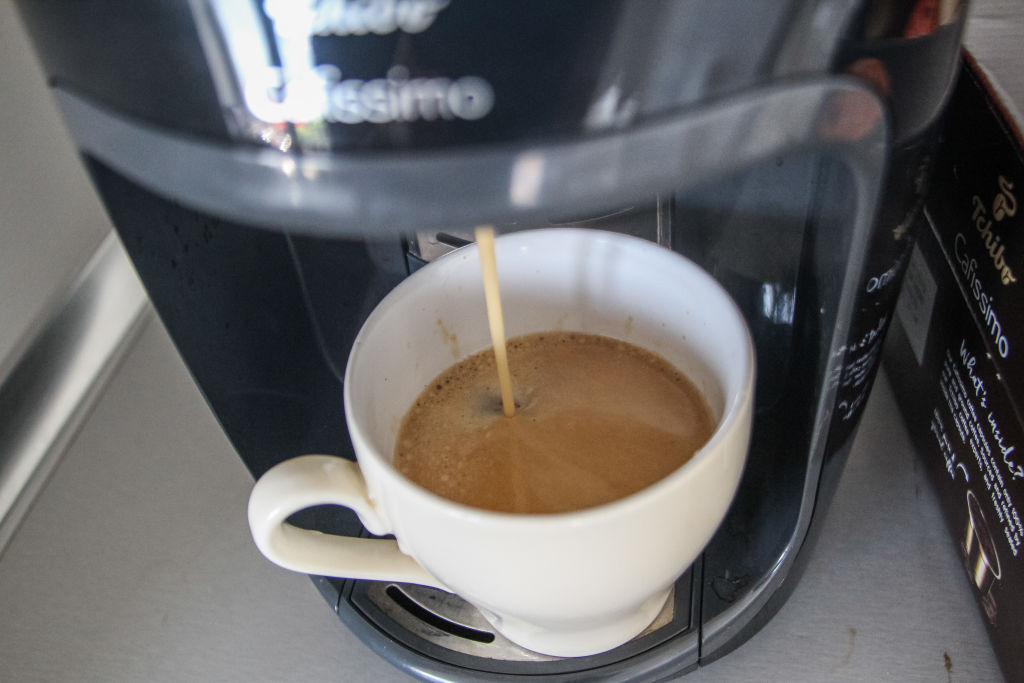 a cup of coffee getting filled by a coffee maker