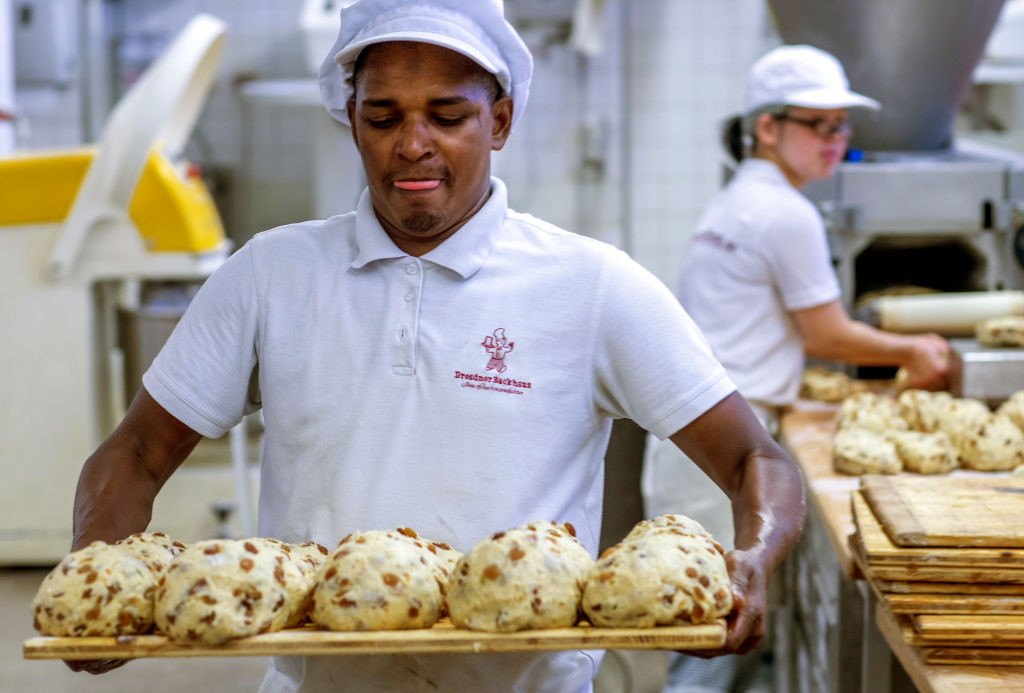 a baker holding five things of dough about to go in the oven