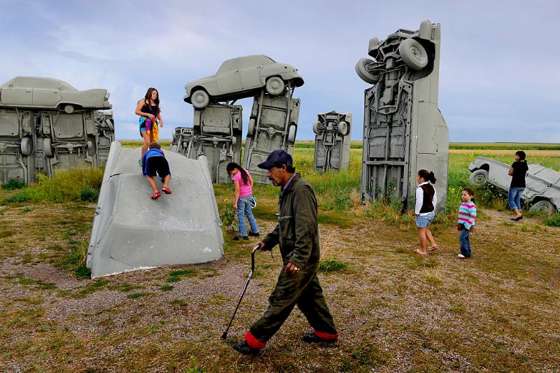 a family playing around the car sculptures at carhenge