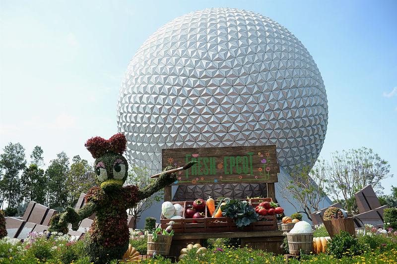 a flower sculpture of daisy duck in front of the epcot center at walt disney world