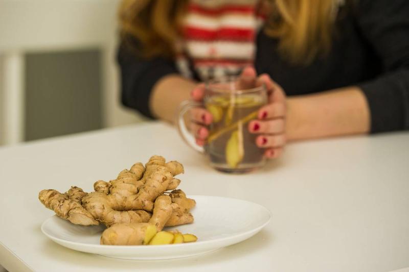 A woman makes ginger tea with fresh ginger laid out on the table.