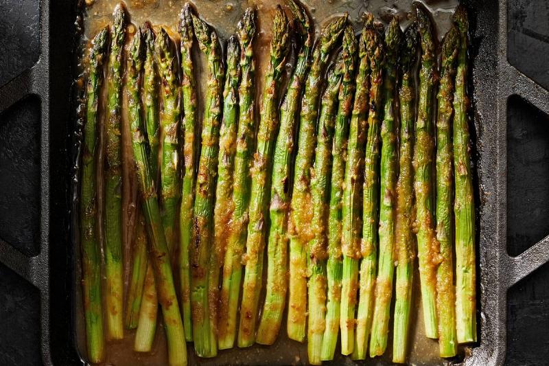 A pan of asparagus cooks in oil.
