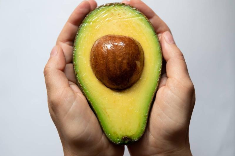 A person holds an avocado half.