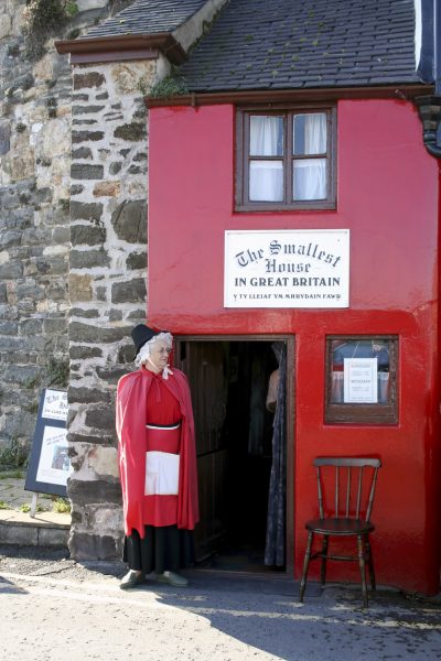 A lady dressed in welsh costume can be seen outside the house.
