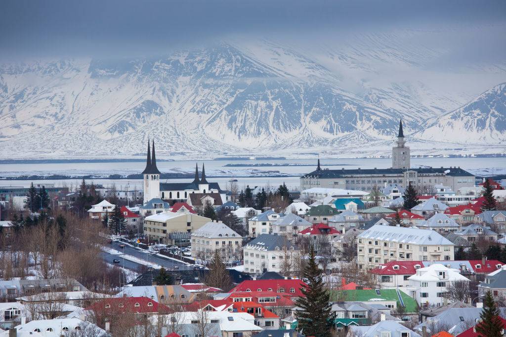 The capital city of Reykjavik, Iceland with traditional bright coloured rooves and snow-covered glacier mountains