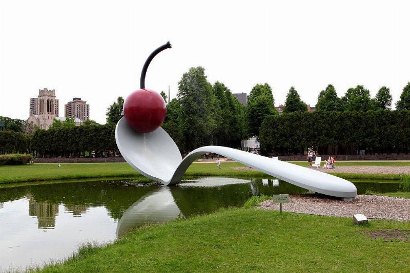 a sculpture of a spoon holding a cherry at a park in minneapolis, minnesota