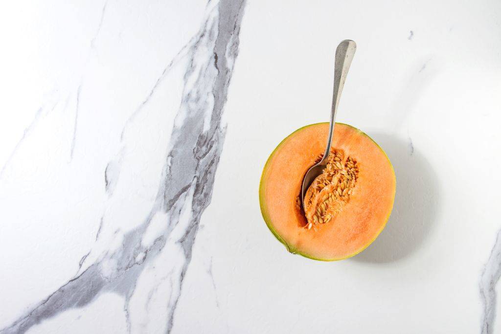 Half of ripe organic Cantaloupe melon with seeds and spoon inside