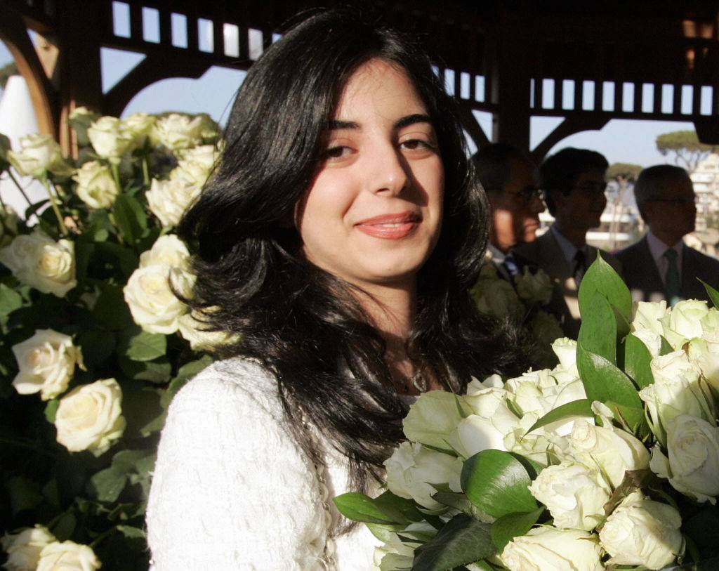 holds a bouquet of white flowers 