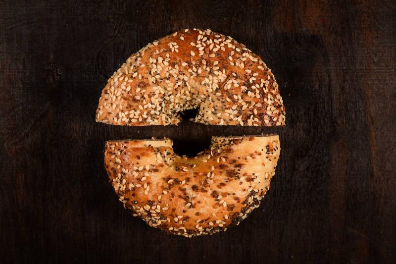 A person removes a slice of a cinnamon sugar bagel.