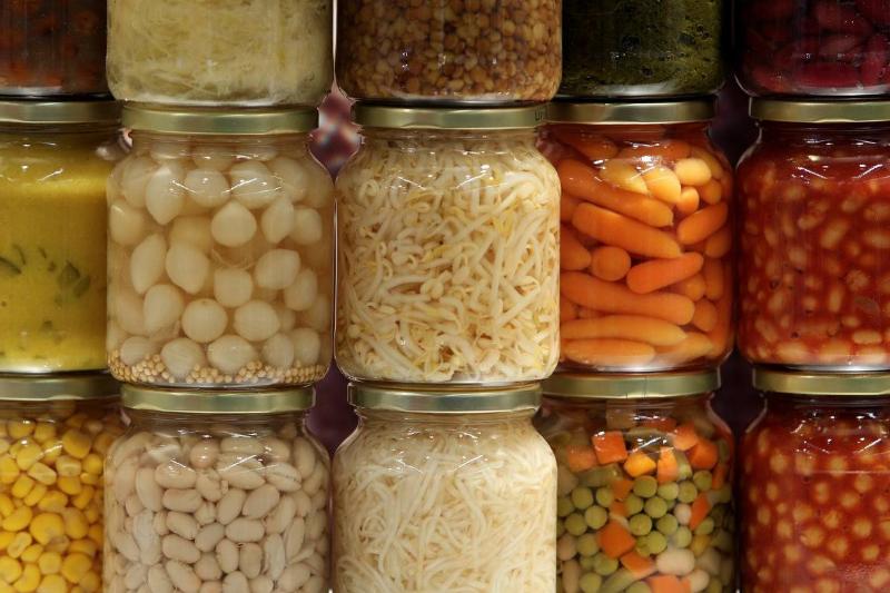 A woman pours canned tomatoes into a soup.