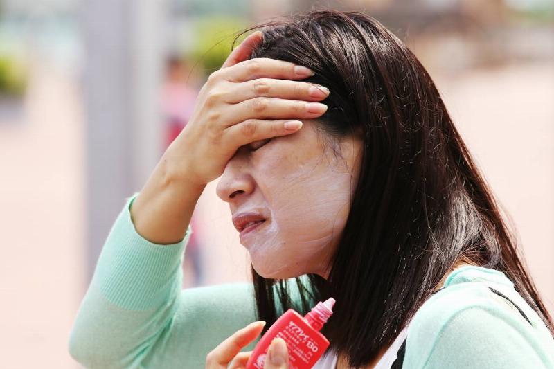 A woman rubs sunscreen on her face.