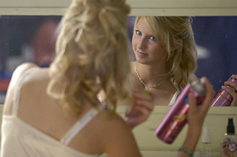 A woman sprays her hair with product.