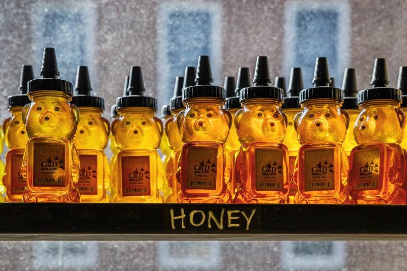 Containers of honey sit on a shelf in a store.