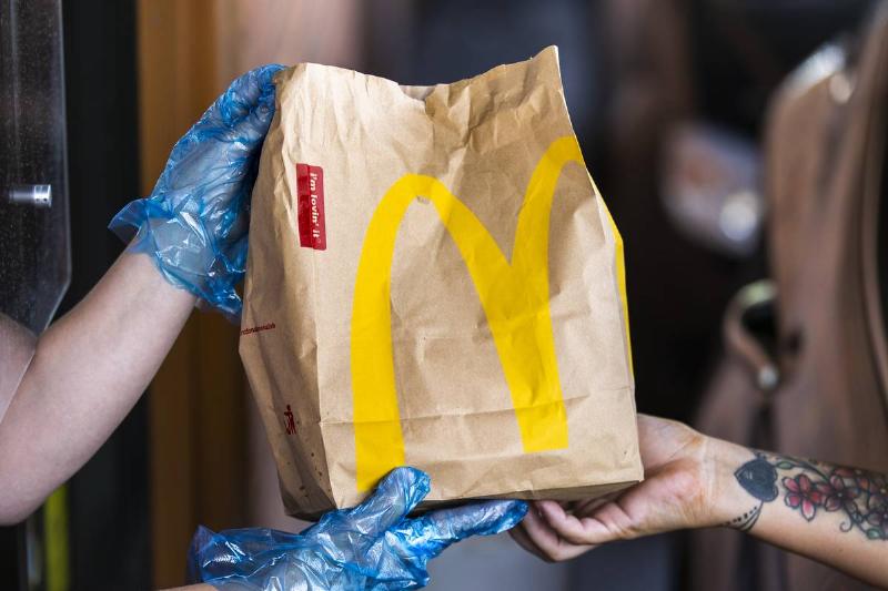 A McDonald's employee hands a customer soda through the drive-thru.
