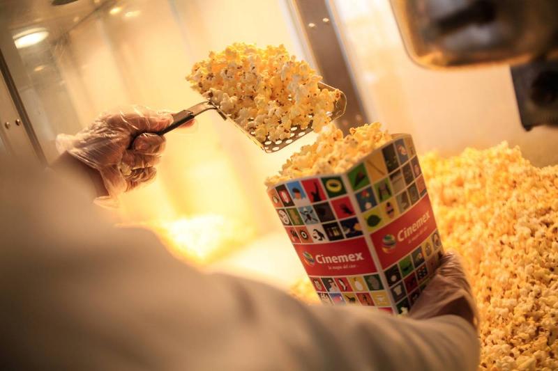 A movie theater employee dishes popcorn into a bag.