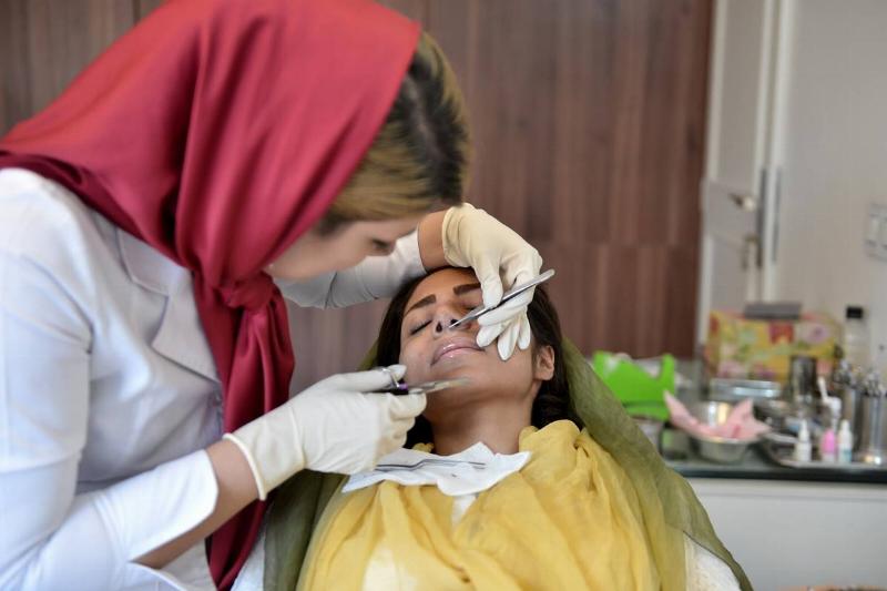 A woman receives a nose job.