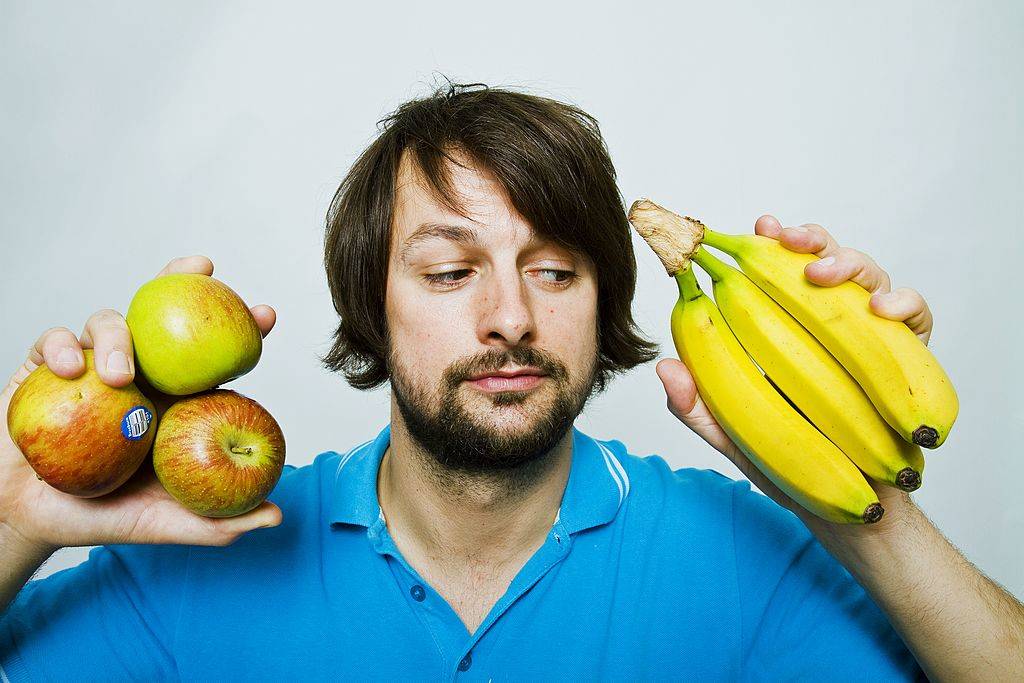 Man deciding whether to eat apple or banana