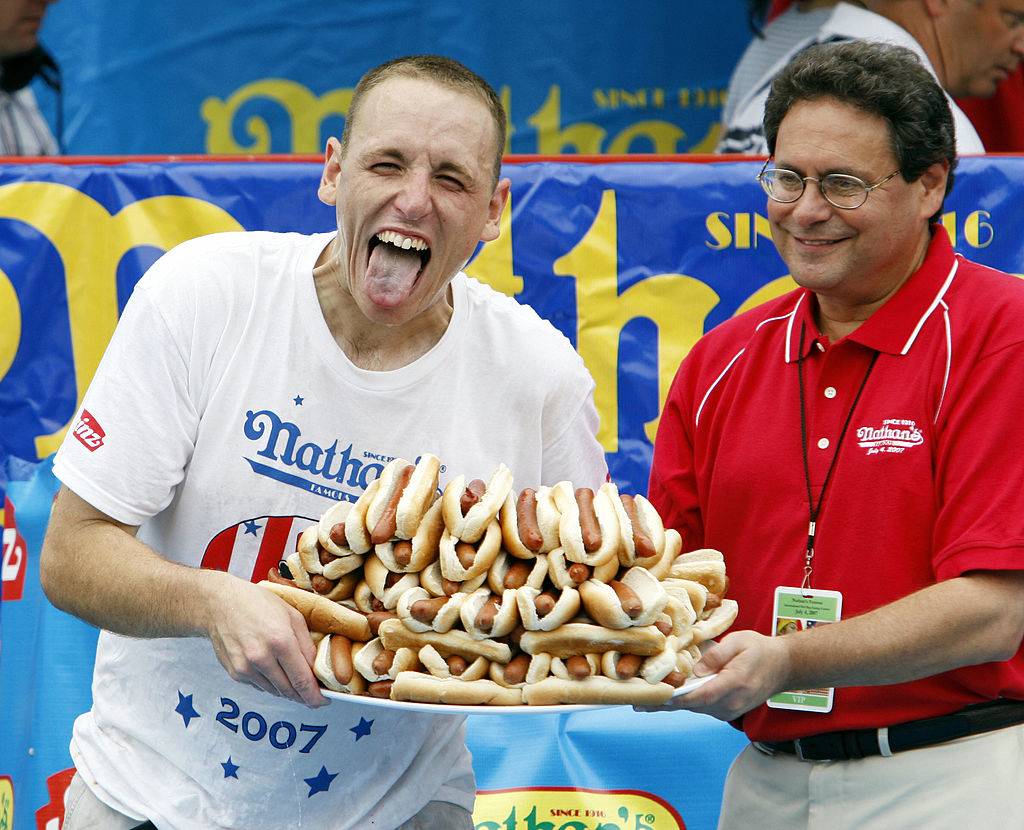Joey Chestnut holding a plate of 66 hot dogs